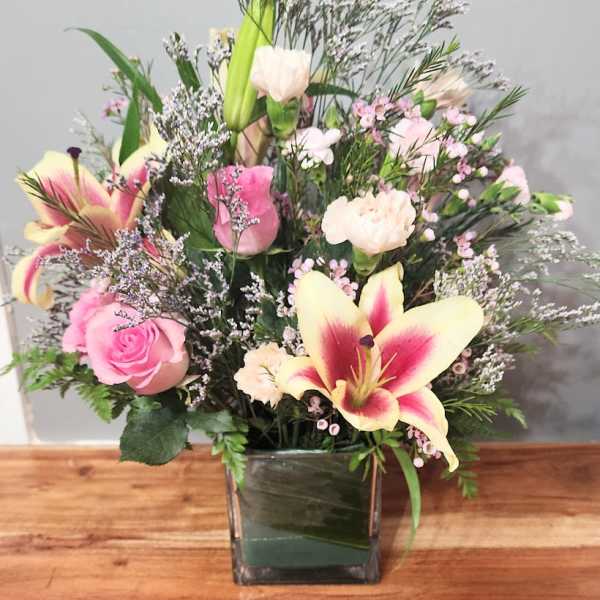 Pink and cream floral arrangement in a square glass vase