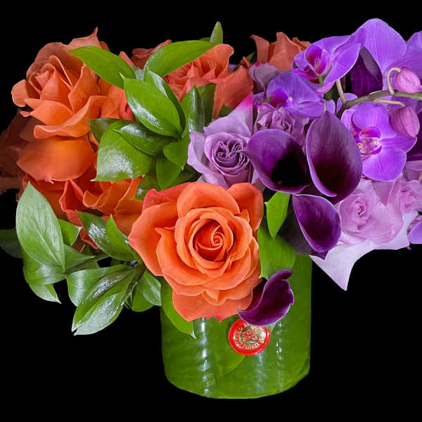 Orange roses and purple orchids in a green vase