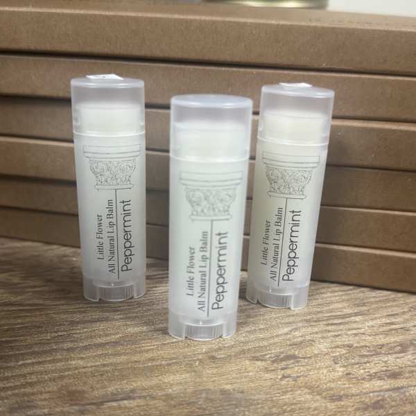 Three peppermint lip balm tubes on a wooden surface