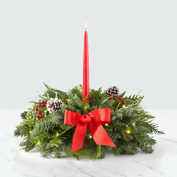Holiday centerpiece with a red taper candle and evergreen wreath