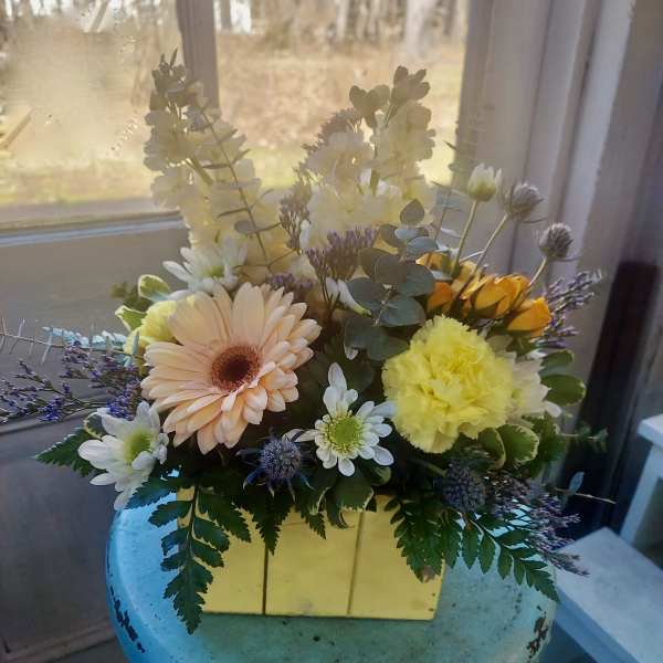 Mixed bouquet in a yellow box with daisies and carnations