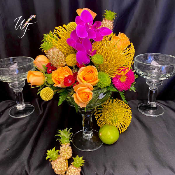 Tropical floral arrangement with roses and orchids in a glass vase