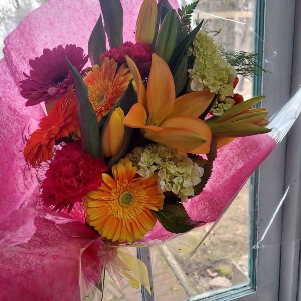 Bouquet of orange lilies, gerbera daisies, and pink chrysanthemums wrapped in pink paper