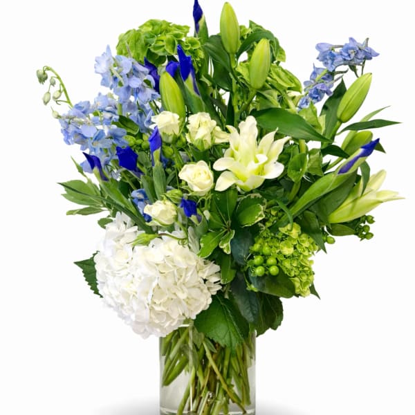 Blue and white mixed flower arrangement in a clear glass vase