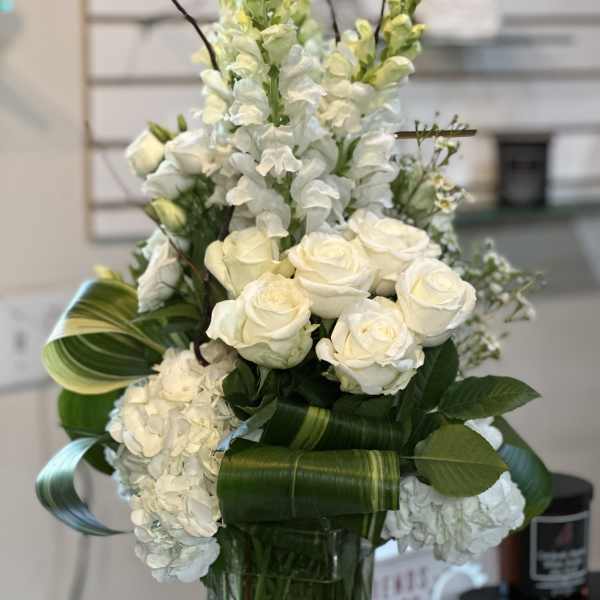 White roses and snapdragons arranged in a glass vase