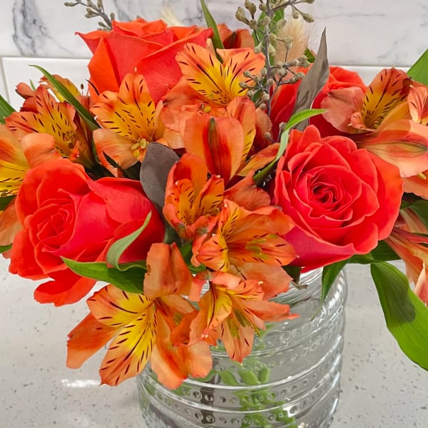 Orange roses and alstroemeria in a clear glass vase