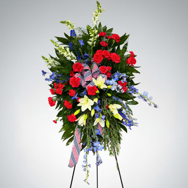 Standing floral spray with red, white, and blue flowers on a tripod easel
