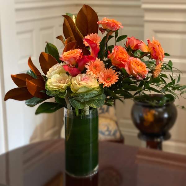 Orange and pink mixed bouquet in a tall glass vase