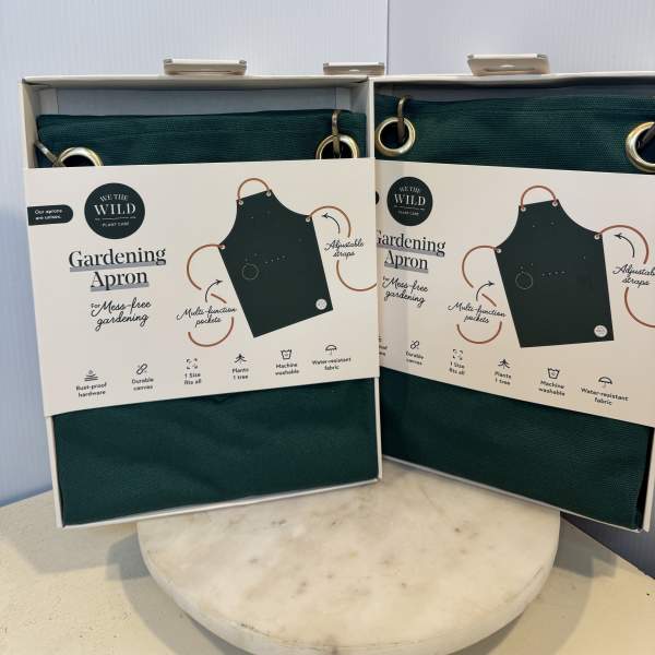 Two boxed green gardening aprons on a table