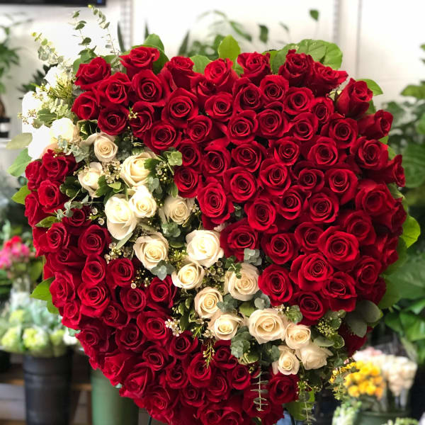 Heart-shaped arrangement of red and white roses on a stand