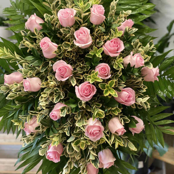 Pink roses arranged in a dense standing spray with variegated foliage