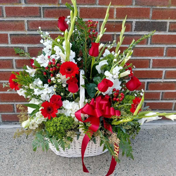 Basket arrangement of red roses, white flowers, and a red ribbon