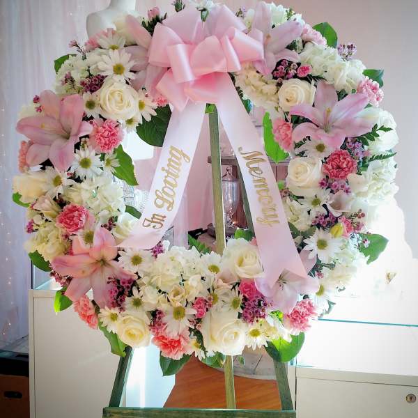 Pink and white floral wreath with a large bow on an easel