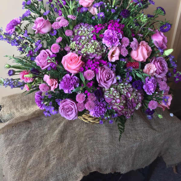 Large bouquet of pink and purple flowers in a basket