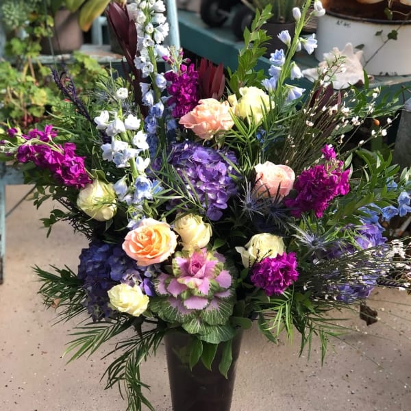 Tall mixed bouquet in a glass vase with roses and purple blooms