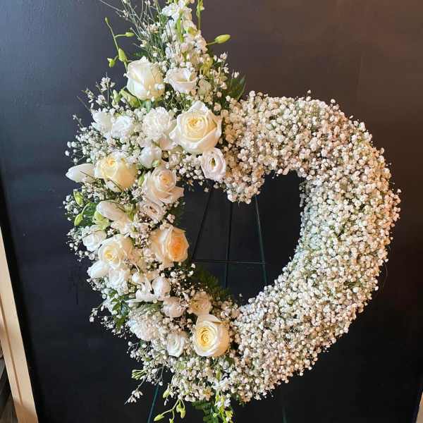 White floral wreath on a stand with roses and baby's breath