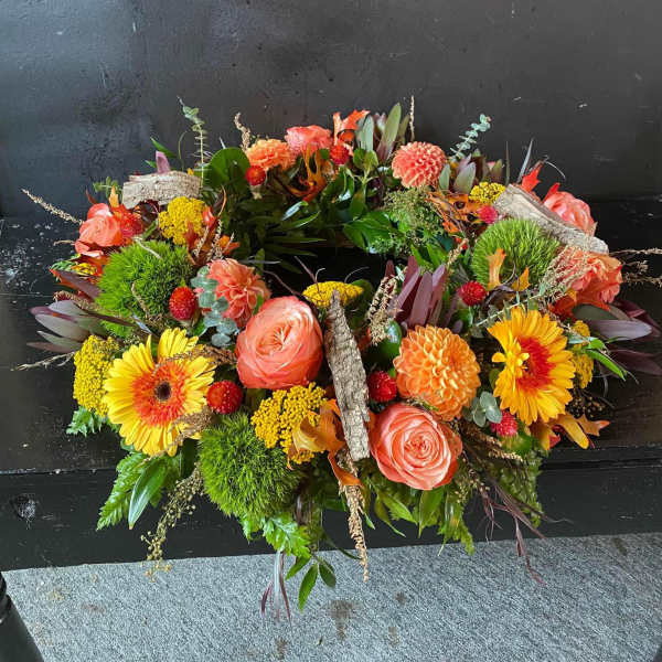 Circular floral wreath with orange and yellow blooms on a dark surface