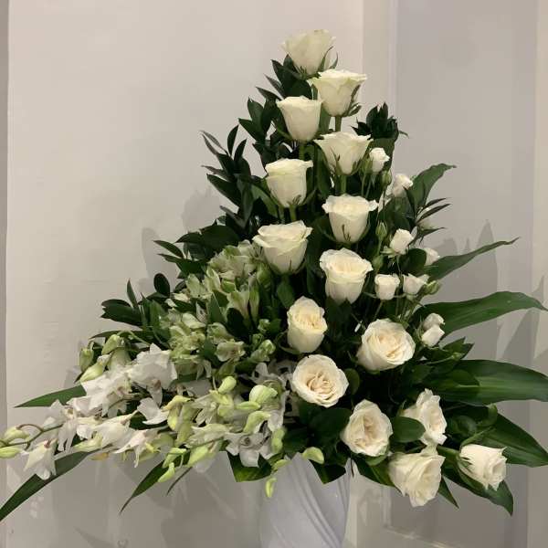 Tall white rose arrangement with orchids in a white vase