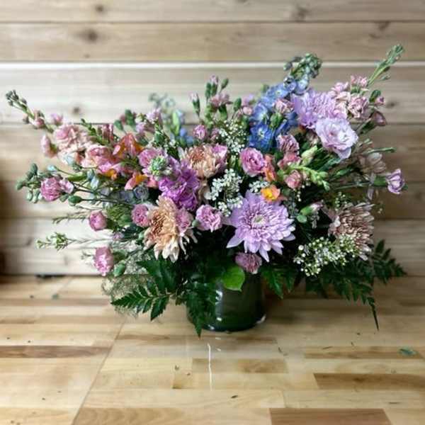 Mixed pastel bouquet in a dark vase on a wooden floor