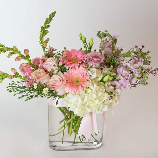 Pink and white mixed bouquet in a clear glass vase with a ribbon