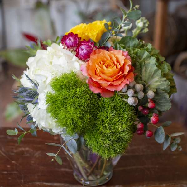 Colorful bouquet in a clear glass vase with orange, white, yellow, and pink blooms