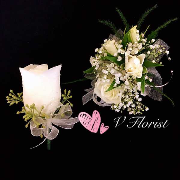 White rose boutonniere and matching wrist corsage with white ribbons on a black background.