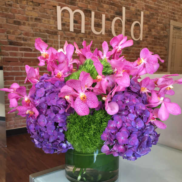 Pink orchids and purple hydrangeas in a glass vase