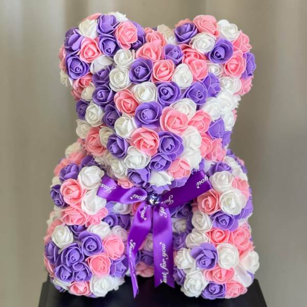 Teddy bear made of pink, purple, and white roses with a purple ribbon