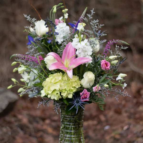 Mixed bouquet in a clear glass vase with pink lily and white blooms