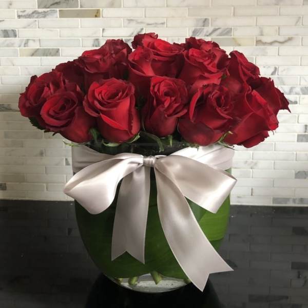 Bouquet of red roses in a glass vase with a satin ribbon