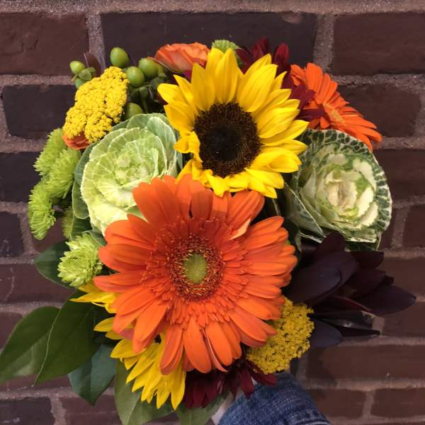 Bouquet of sunflowers, orange gerbera daisies, and green ornamental cabbage