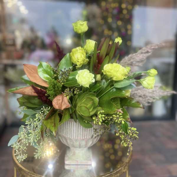 Green and lime floral arrangement in a white pedestal vase