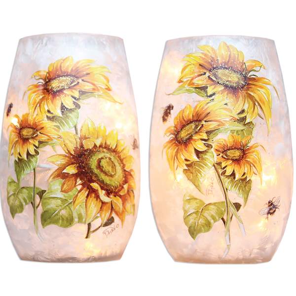 Pair of sunflower-decorated glass candle holders glowing softly