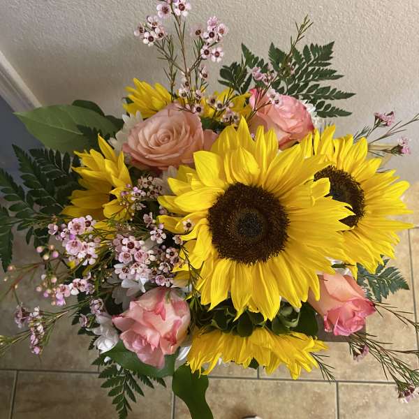 Bouquet of sunflowers, pink roses, and small pink filler flowers