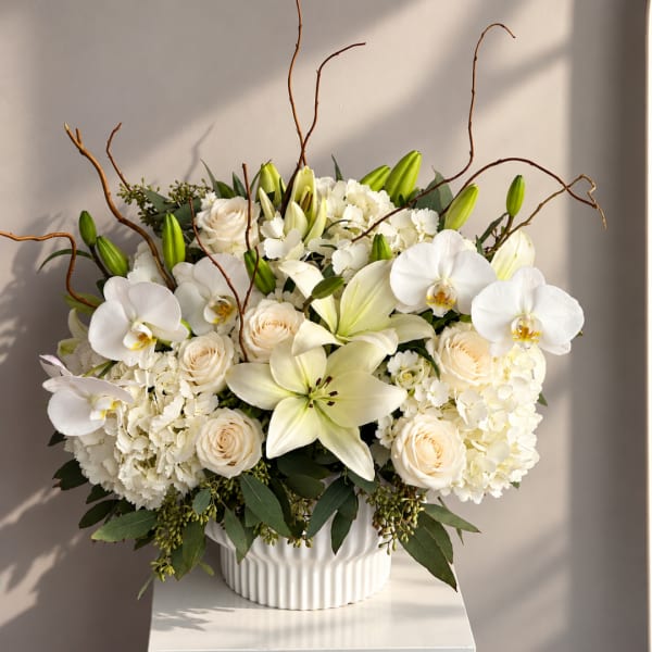 White lilies, orchids, roses, and hydrangeas in a white vase