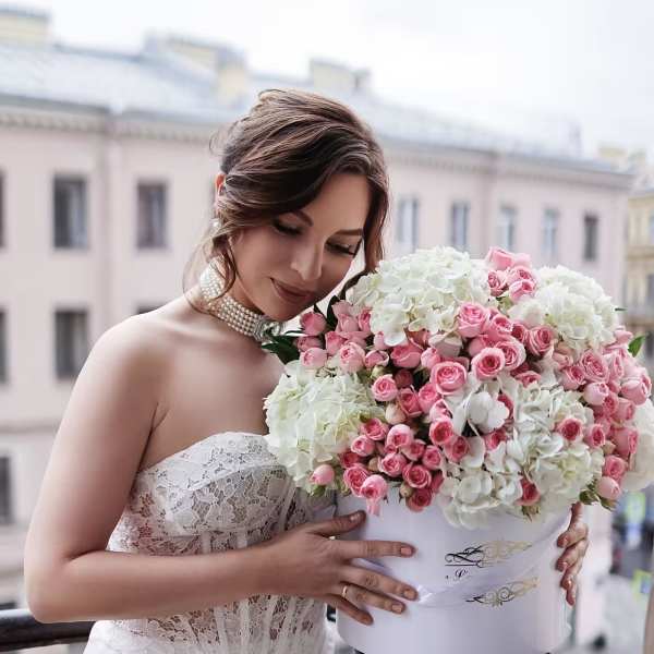 Bride holding a large pink and white rose bouquet in a white box