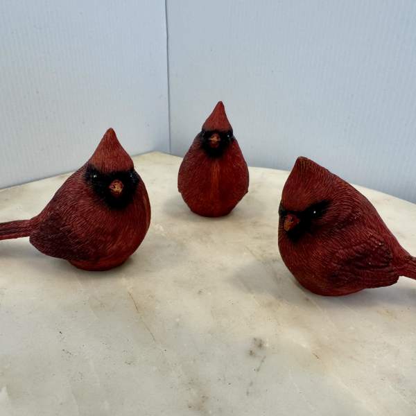 Three red decorative bird figurines on a light surface