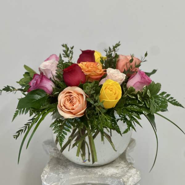 Mixed roses arranged in a round white vase