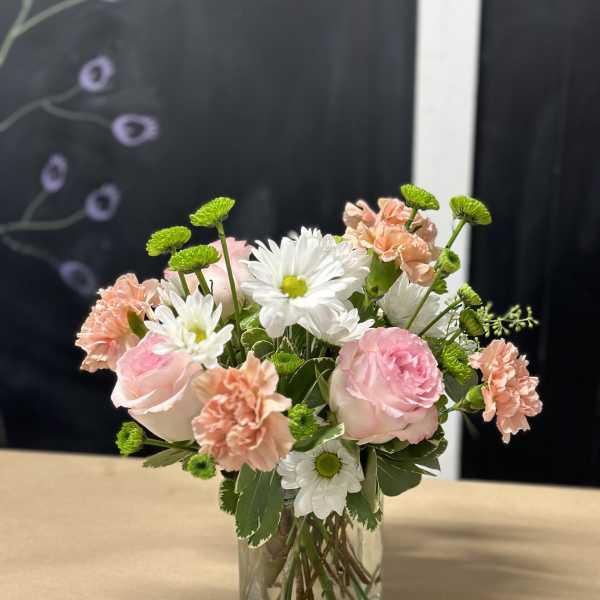 Pink and white flowers arranged in a clear glass vase