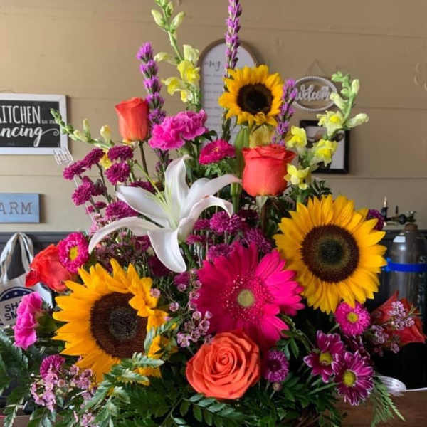 Basket arrangement with sunflowers, roses, lilies, and pink mixed blooms