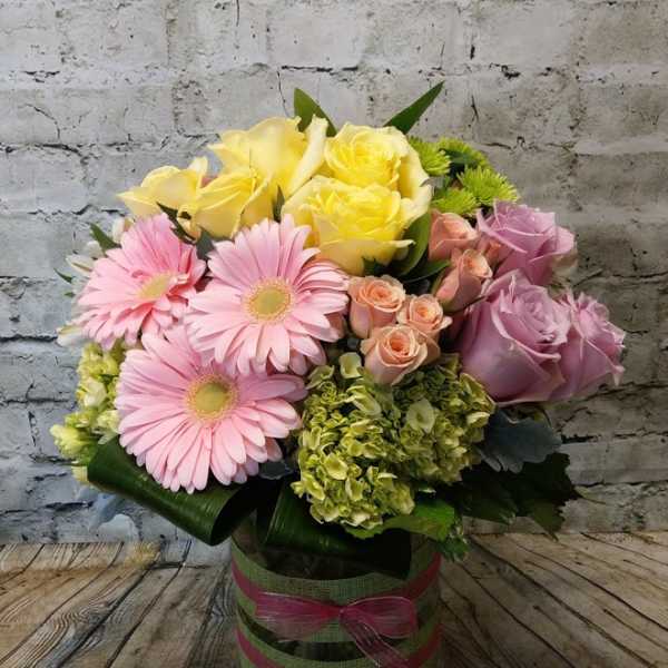 Bouquet of pink and yellow flowers in a glass vase with ribbon