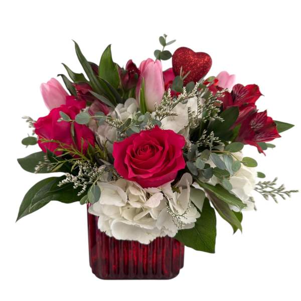 Pink and white flower arrangement in a red vase with a glitter heart pick