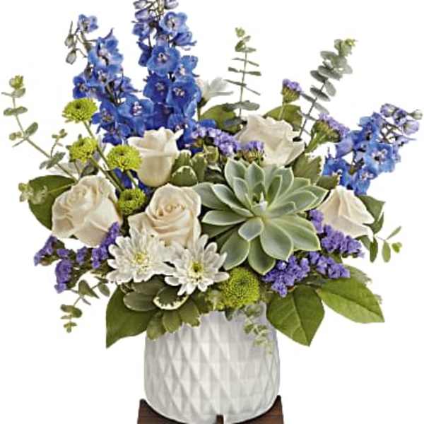 Blue and white floral arrangement in a white vase with a succulent