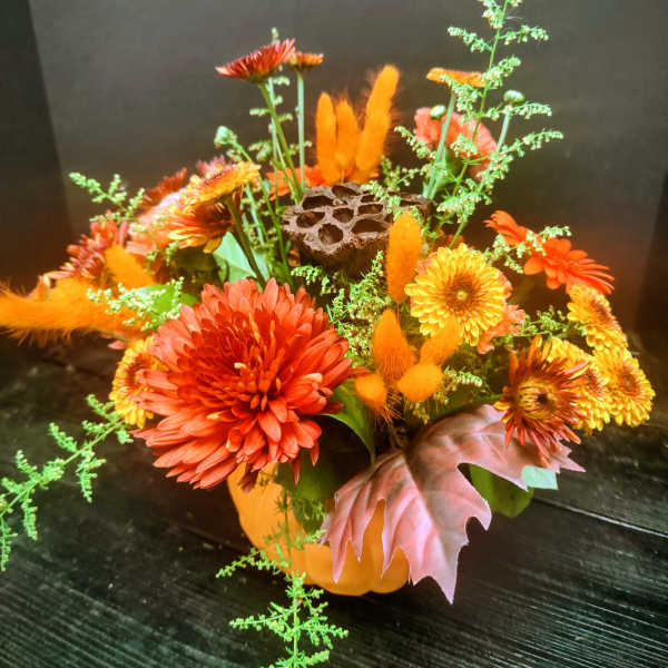 Orange and yellow chrysanthemum arrangement in a pumpkin container