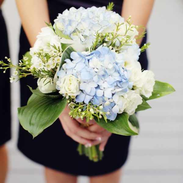 Woman holding a bouquet of pale blue hydrangeas and white roses