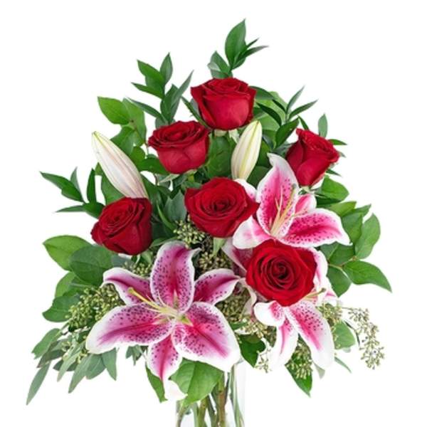 Red roses and pink lilies arranged in a clear glass vase