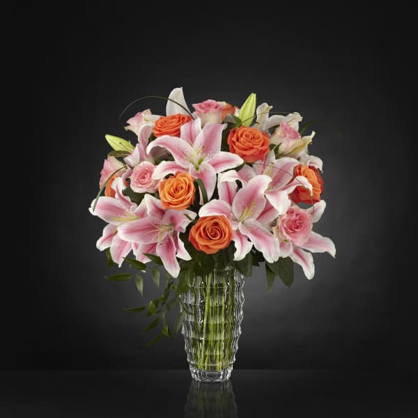 Pink lilies and orange roses in a clear glass vase