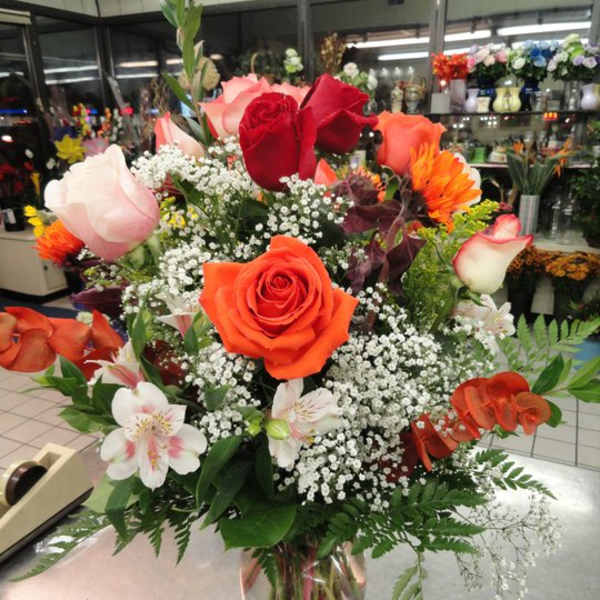 Mixed bouquet of roses and white filler flowers in a clear glass vase