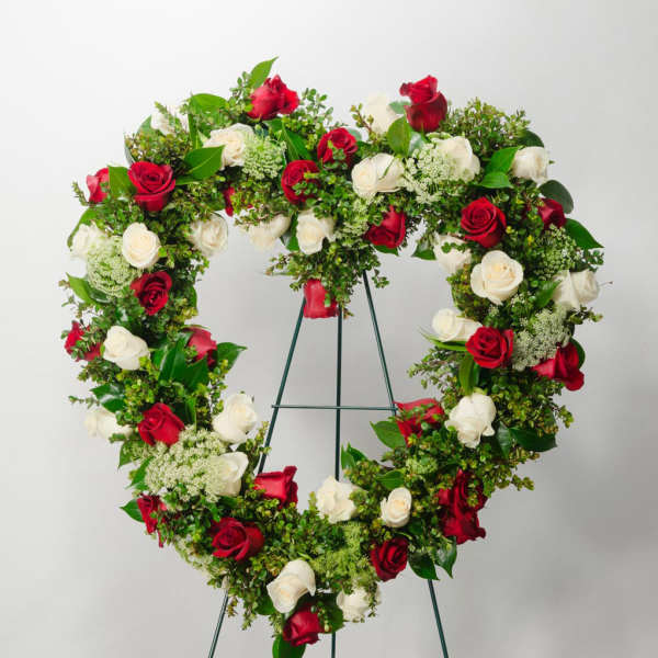 Heart-shaped wreath of red and white roses on a stand