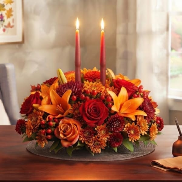 Autumn floral centerpiece with two lit candles in a low round arrangement
